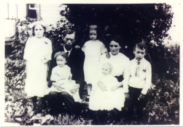 A black and white image of two parents with five children.