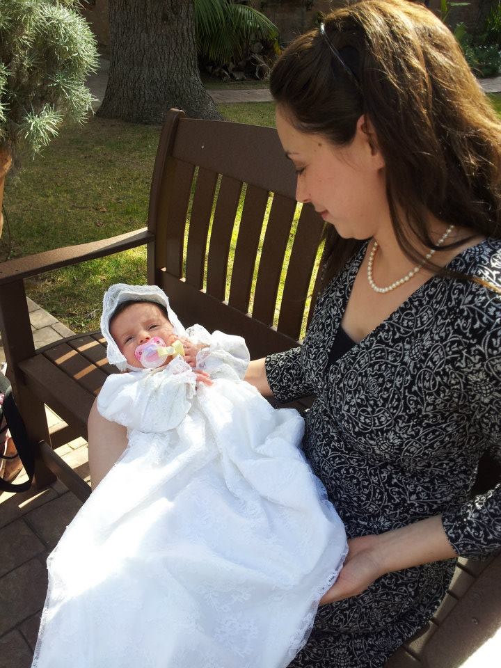 A young mother holds her baby outside a church on baptism day.