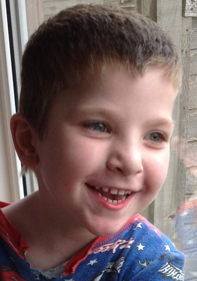 A young boy smiles as he looks outside.