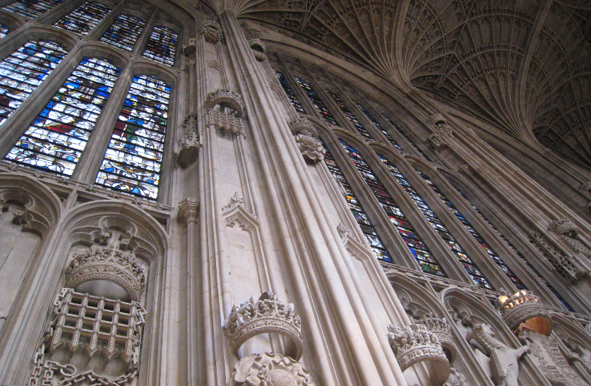 The inside of a very ornate church with extensive stone work and stone glass windows.