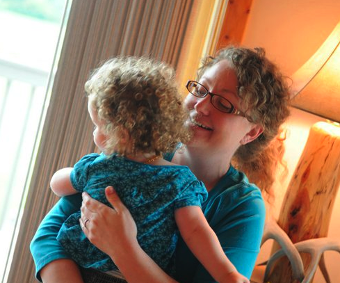 Curly-haired mother and child look out the window.