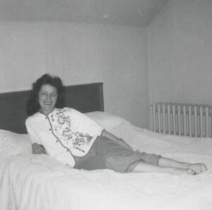 An old photo of a woman casually relaxing on a bed