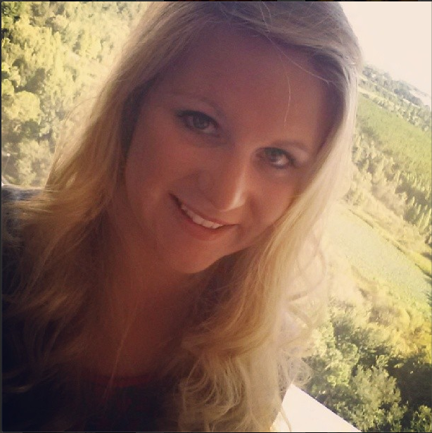 A nurse smiles with beautiful green trees in the background