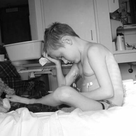 A child in a hospital bed looks sad