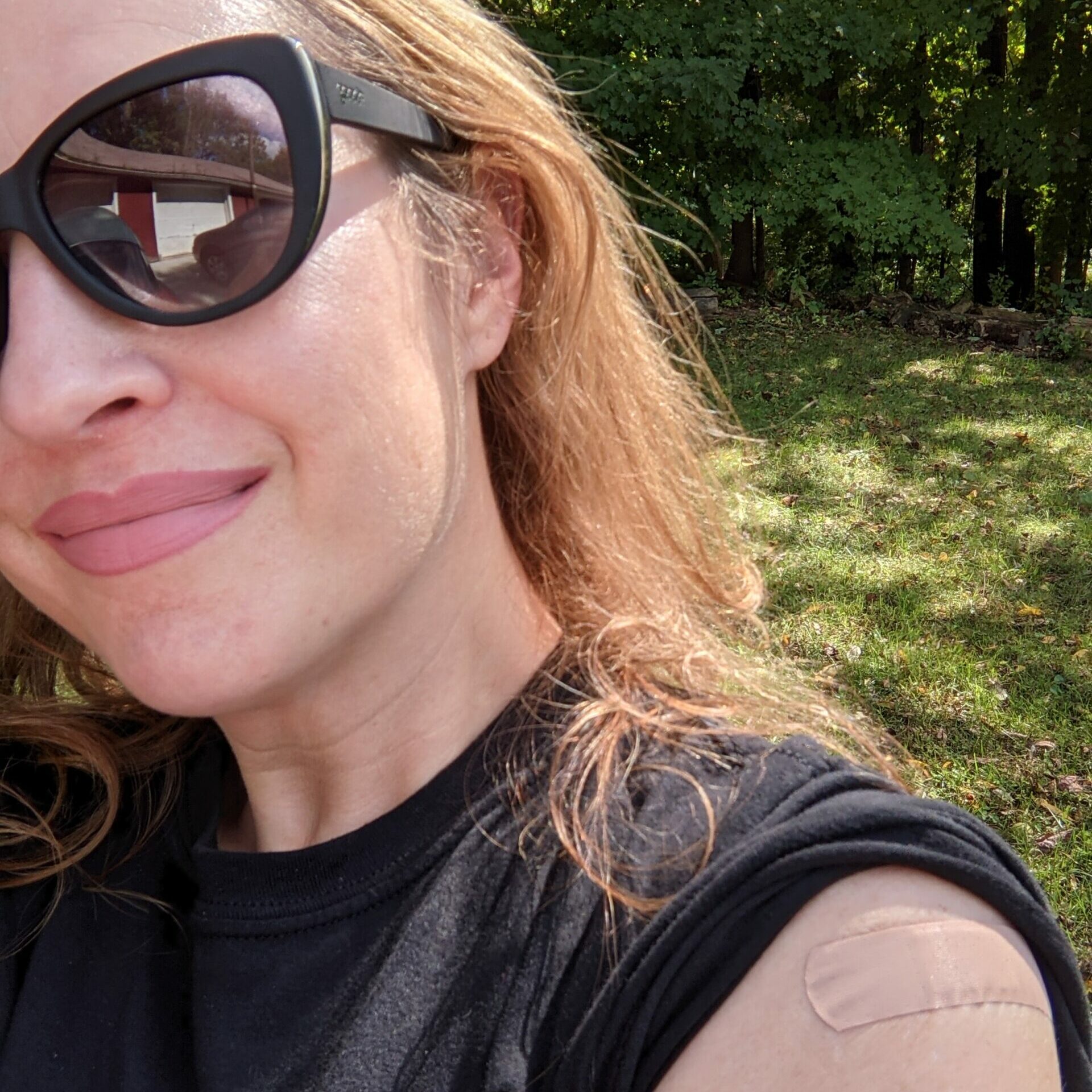 Tara Smith wearing sunglasses and black shirt with a bandaid on her arm.