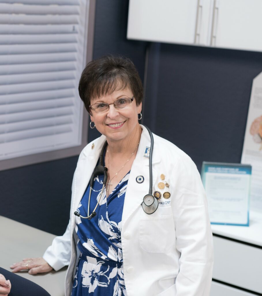 Mary, a female doctor in a white coat and flowered scrubs.