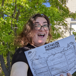 Brittany Lindstrom holds a picture of a dragon and books on a bookshelf that says oceans of possibilities