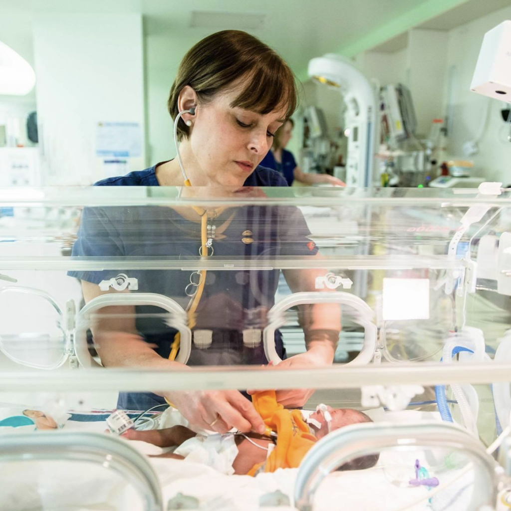 A female nurse applies a stethoscope to a baby in the hospital.