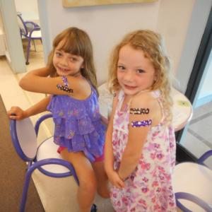 Two small children show off the bandages from getting vaccinated