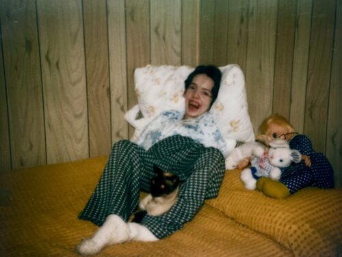 Young woman smiling with a cat on her lap.