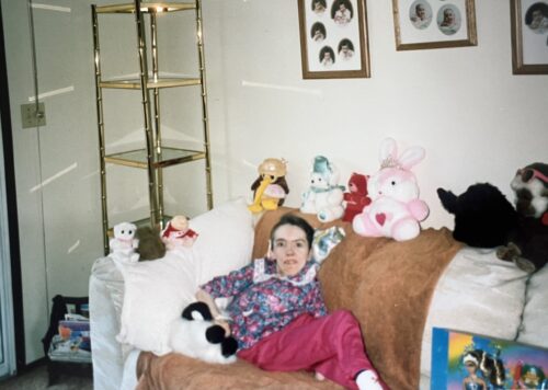 Woman resting on a couch surrounded by stuffed animals.