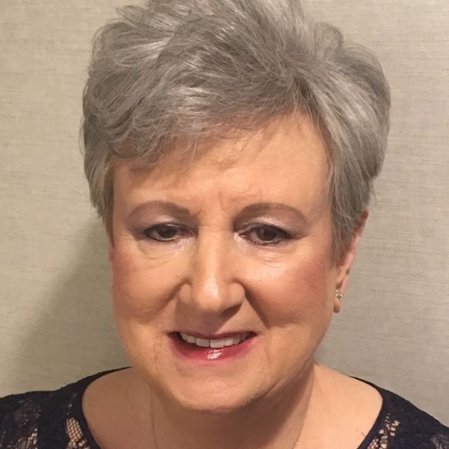 Lynne Sandler, smiling, with short gray hair and a dark lace top.