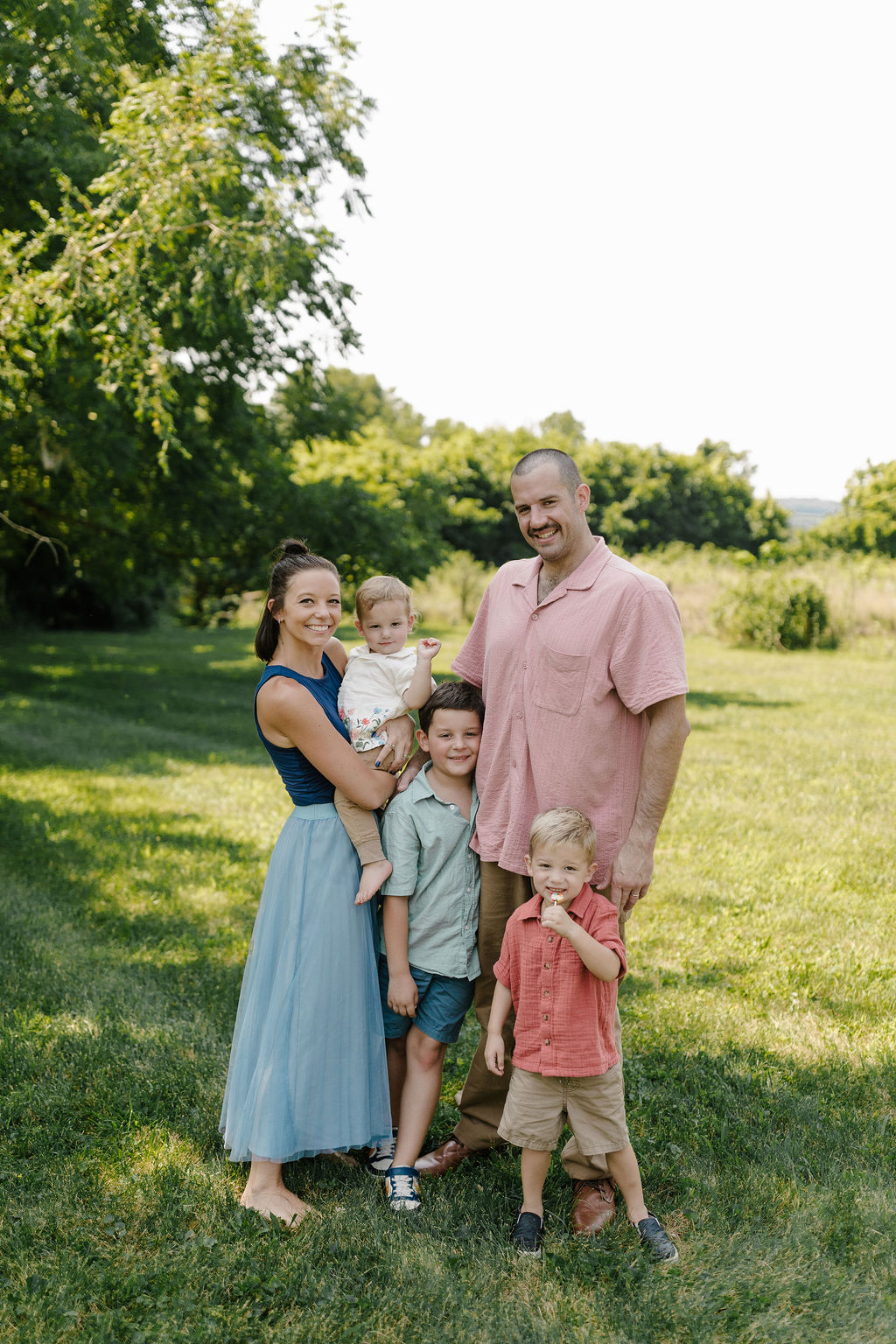 Morgan, her husband Josh and their three young sons standing together on a grassy lawn in summer